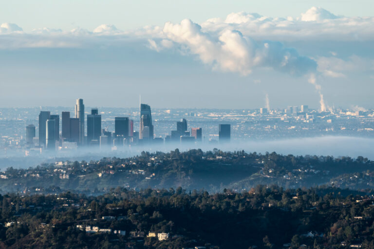 Foggy morning skyline view of downtown Los Angeles with steaming South Bay refineries and industrial facilities in background. Photo taken from hilltop near Pasadena, California.