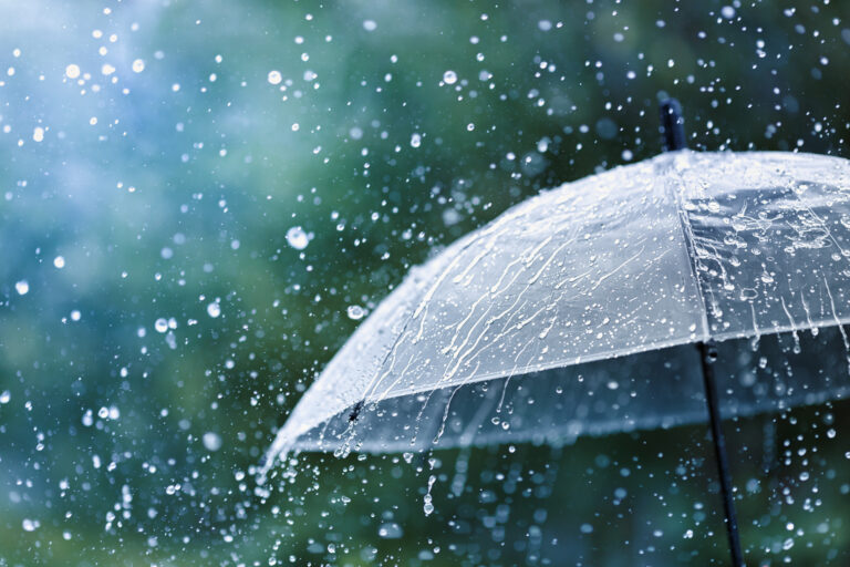 Transparent umbrella under rain against water drops splash backg